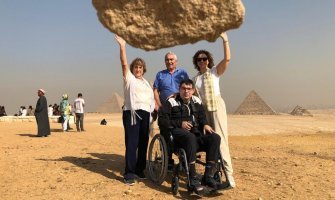 Una familia de viaje en Egipto, uno de los integrantes es un usuario de silla de ruedas, se ve al fondo la pirámide