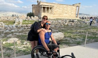 Un usuario de silla de ruedas junto a su mujer visitando sitios arqueológicos an Atenas