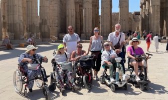 Grupo de viajeros usuarios de silla de ruedas en un viaje adaptado a Egipto frente a un templo con columnas