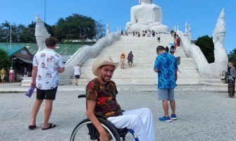 Viajero en silla de ruedas en un templo en Tailandia con un Buda al fondo