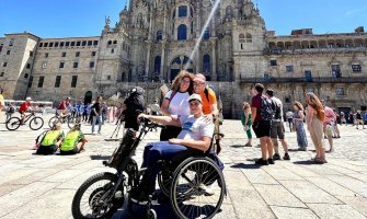 Un usuario de silla de ruedas posa con sus padres frente a la Catedral de Santiago de Compostela