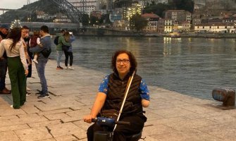 Una viajera con discapacidad en su scooter eléctrico con la ciudad de Oporto al fondo