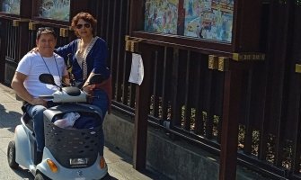 Una pareja, uno de ellos sentado sobre un scooter, posando frente a un monumento en Japón