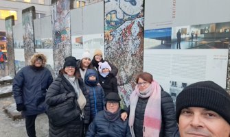 Una familia realizando un selfie con restos del muro de Berlin al fondo