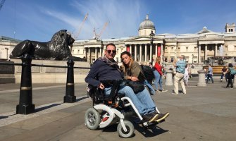 Un usuario de silla de ruedas eléctrica con su pareja en Trafalgar Square en Londres