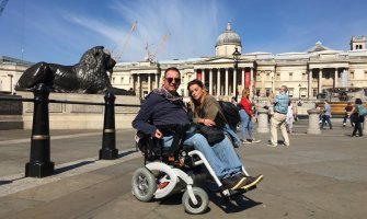 Un usuario de silla de ruedas eléctrica con su pareja en Trafalgar Square en Londres