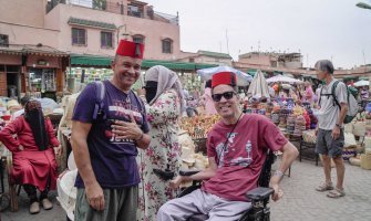 Dos viajeros, uno usuario de silla de ruedas, disfrutando de un viaje accesible en la plaza de Marrakech