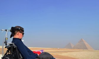 En la foto se ve un usuario de silla de ruedas de viaje en Egipto con la pirámide de Guiza de fondo