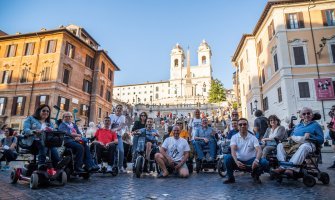 Un grupo de viajeros usuarios de silla de ruedas con la Piaza España de fondo en un viaje grupal a Roma