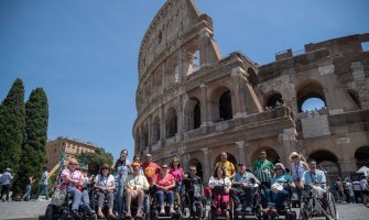 Grupo de viajeros usuarios de silla de ruedas con el coliseo romano al fondo