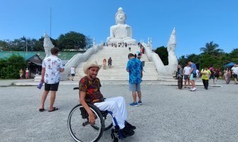 Foto de un usuario de silla de ruedas frente a un templo budista en Tailandia
