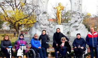 Grupo de silleros en una plaza de Viena y al fondo una estatua dorada tocando el violin