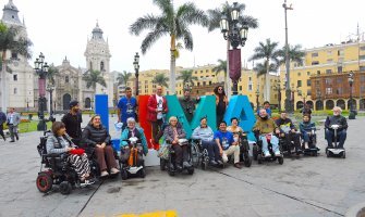 Grupo de viajeros con discapacidad posando frente al cartel de la ciudad de Lima en Peru